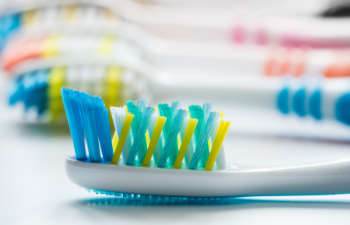 A row of colorful toothbrushes on a white surface.