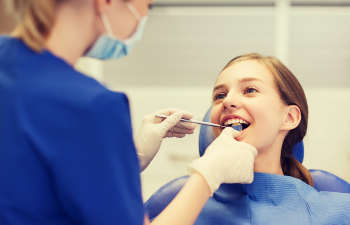 A woman is getting her teeth checked by a dentist.