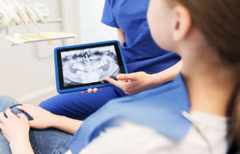 A dentist explaining his patient treatment options using a digital teeth imaging