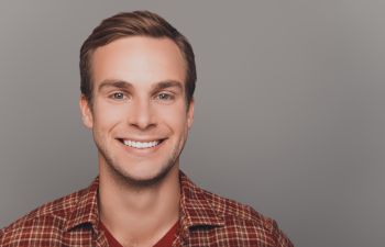 A smiling man in a plaid shirt.