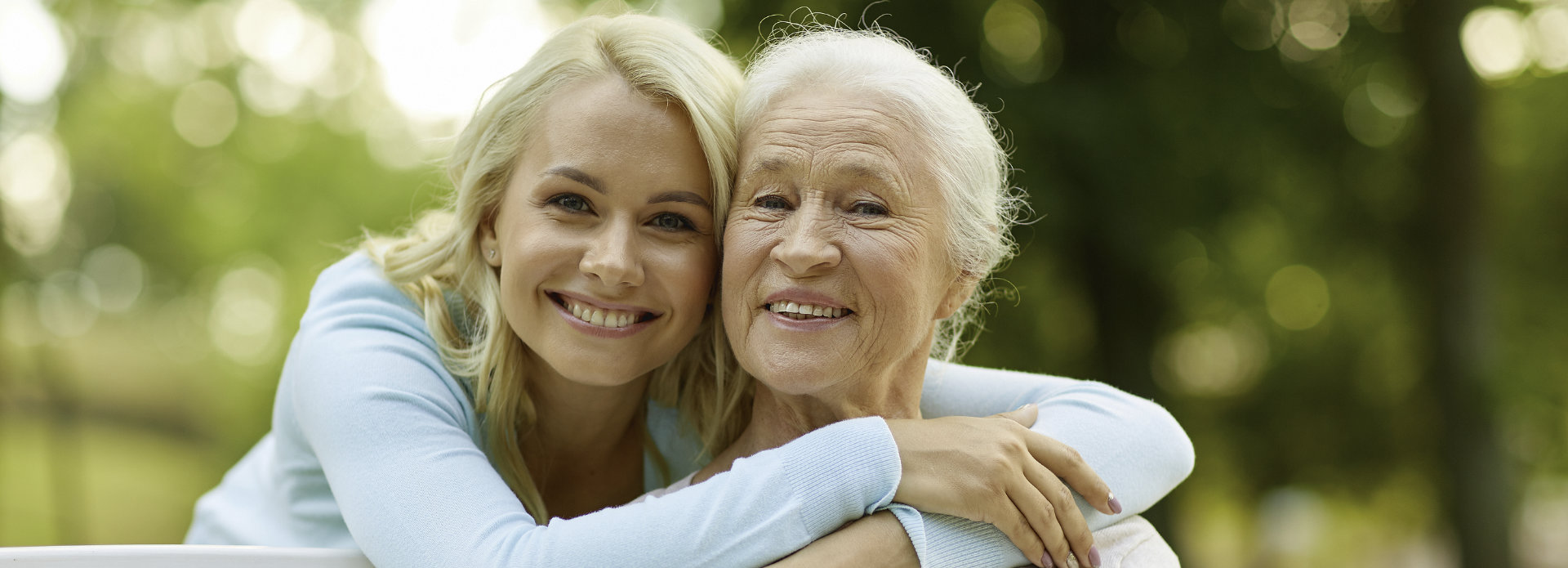 Broadly smiling young woman hugging her grandmother