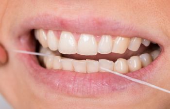 A woman flossing her teeth.