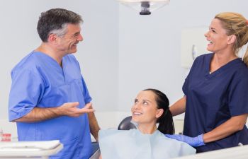 A dentist talking to a patient in a dental chair.