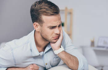 A man with severe toothache rubbing his jaw and cheek with his hand.