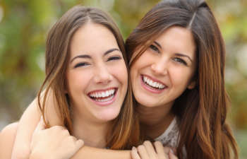 Two smiling women hugging each other.