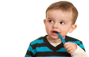 A young boy is brushing his teeth with a blue toothbrush.