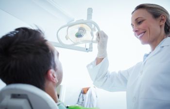 A dentist is looking at a patient in a dental chair.