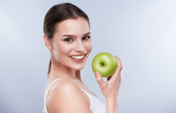 A woman is holding a green apple in her hand.