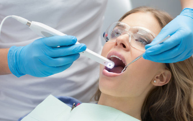 woman dental patient undergoing oral screening with an intraoral camera