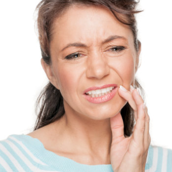 mature woman with dental pain touching her cheek
