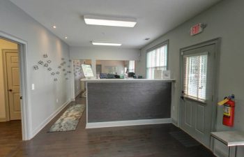 A hallway in a dental office with gray walls and wood floors.
