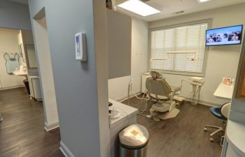 A dentist's office with a tv and a sink.