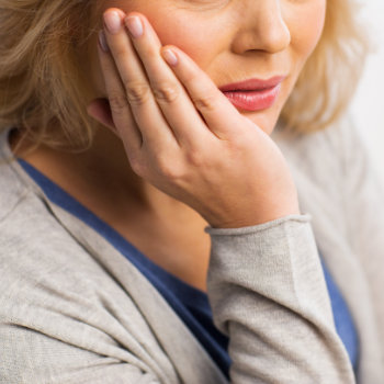 senior woman with dental pain touching her cheek