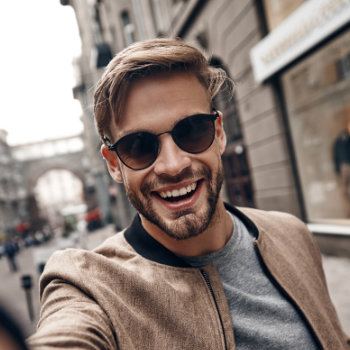 young smiling handsome man in sunglasses walking in the historic part of a city
