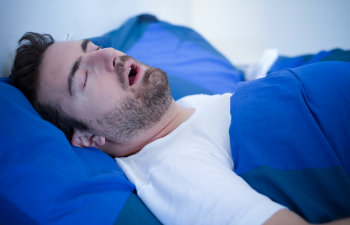 Man in bed suffering for sleep apnea syndrome
