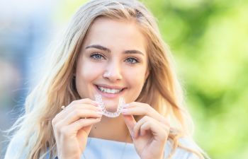 Attractive young woman holding dental clear aligner