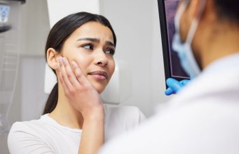 An emergency dentist showing a digital dental image and explaining treatment options to a woman with dental pain