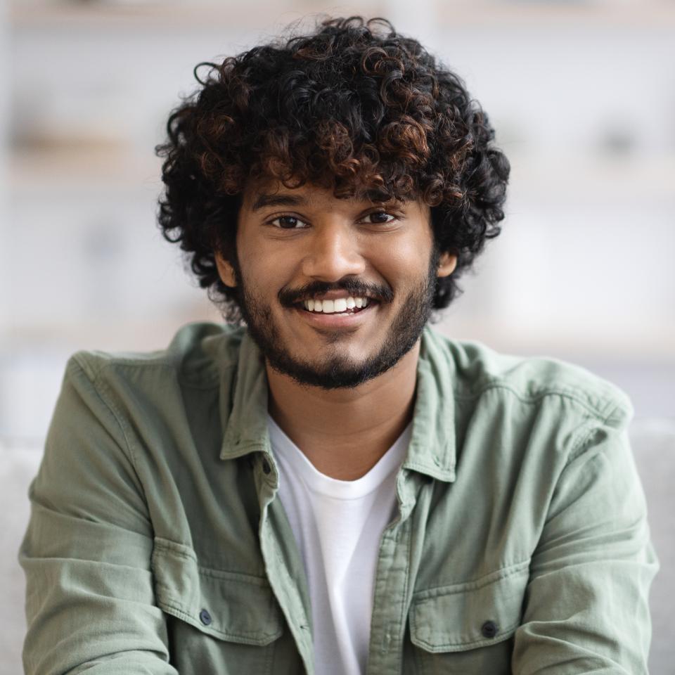 Smiling young man with curly hair and beard
