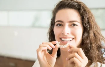 Smiling woman holding clear mouth guard for grinding teeth care
