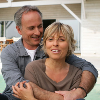 Mature couple sitting in front of house retirement life scene