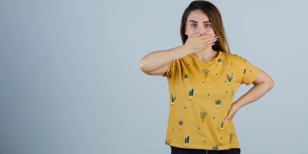 Woman covering mouth from dry mouth bad breath with discomfort