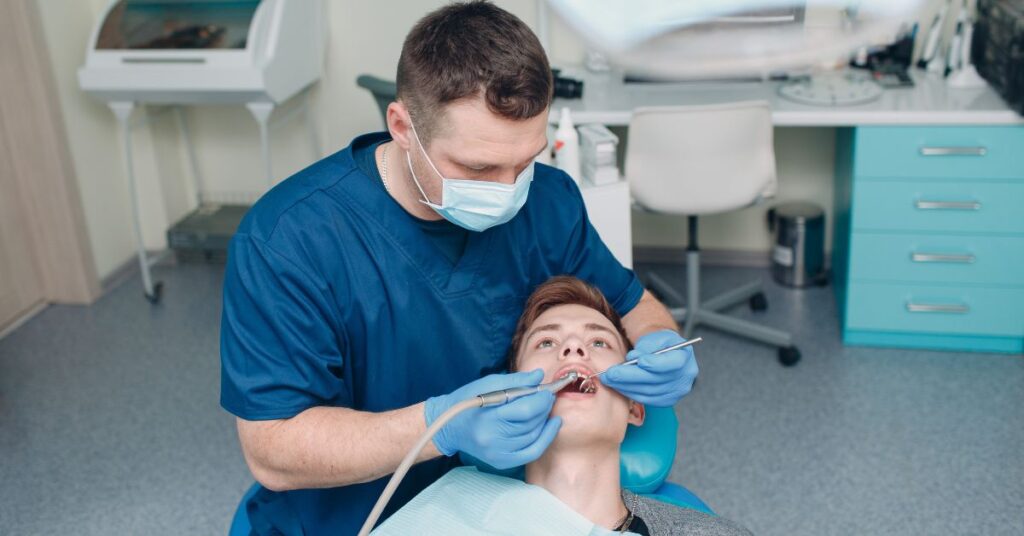 Male dentist performing a routine dental examination on a young patient in a modern dental clinic