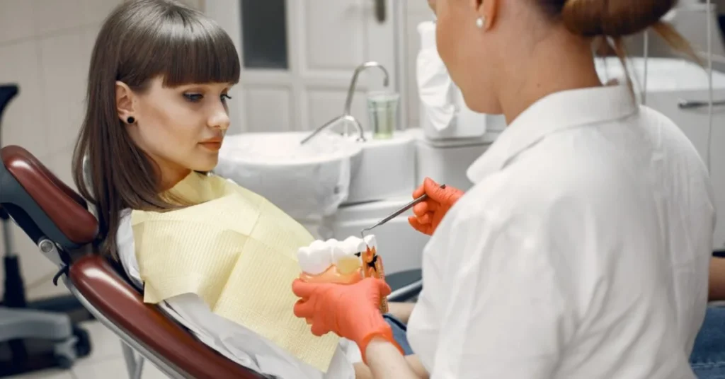 explaining tooth model) Dentist explaining dental composite filling procedure